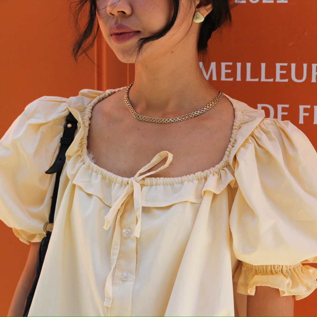 Close-up of the Mathilde ruffled neckline and puff sleeves in pale yellow